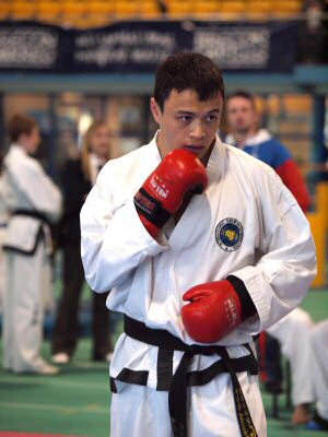 Mr Jonnie Chan ready to spar. Black belt with red sparring equipment on ready with hands up.