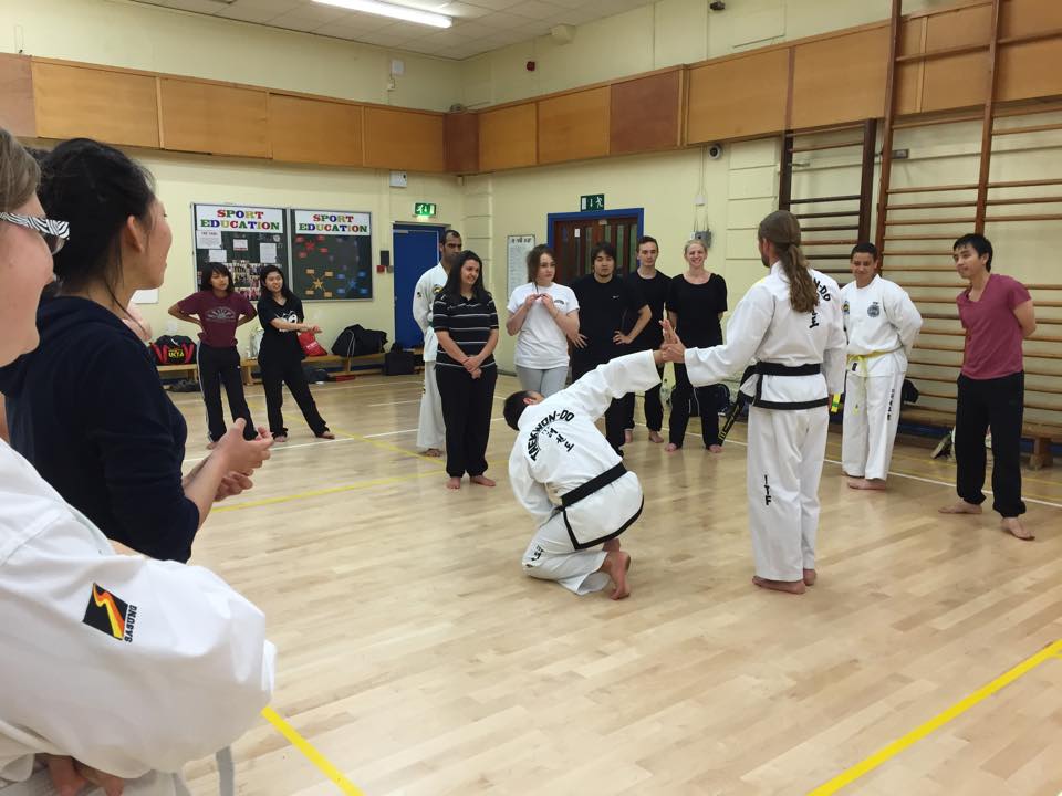 Mr Jeuken teaching a wrist lock to new Taekwon-Do students. He has another student by his wrist and the other student is crouched on the floor.