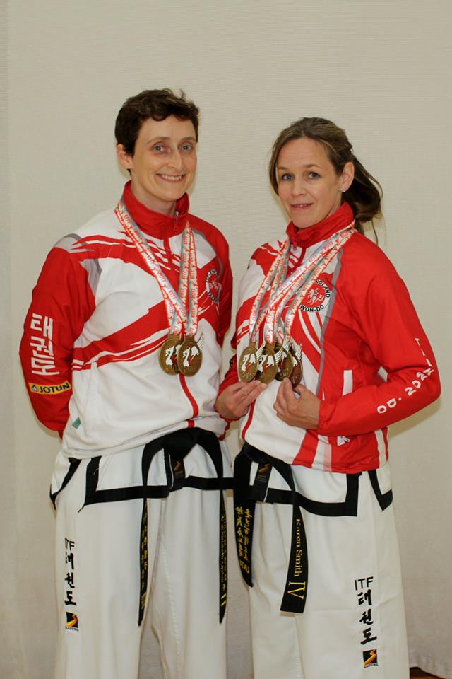 Two female martial artists posing with five gold medals won at the European Championships in Liverpool 2017. Wearing Doboks and ITF England training tops.