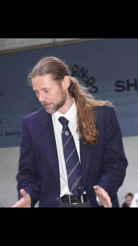 Mr Lars Yeuken V dan wearing his formal Taekwon-Do suite, explaining something with his hands in an explaining gesture.