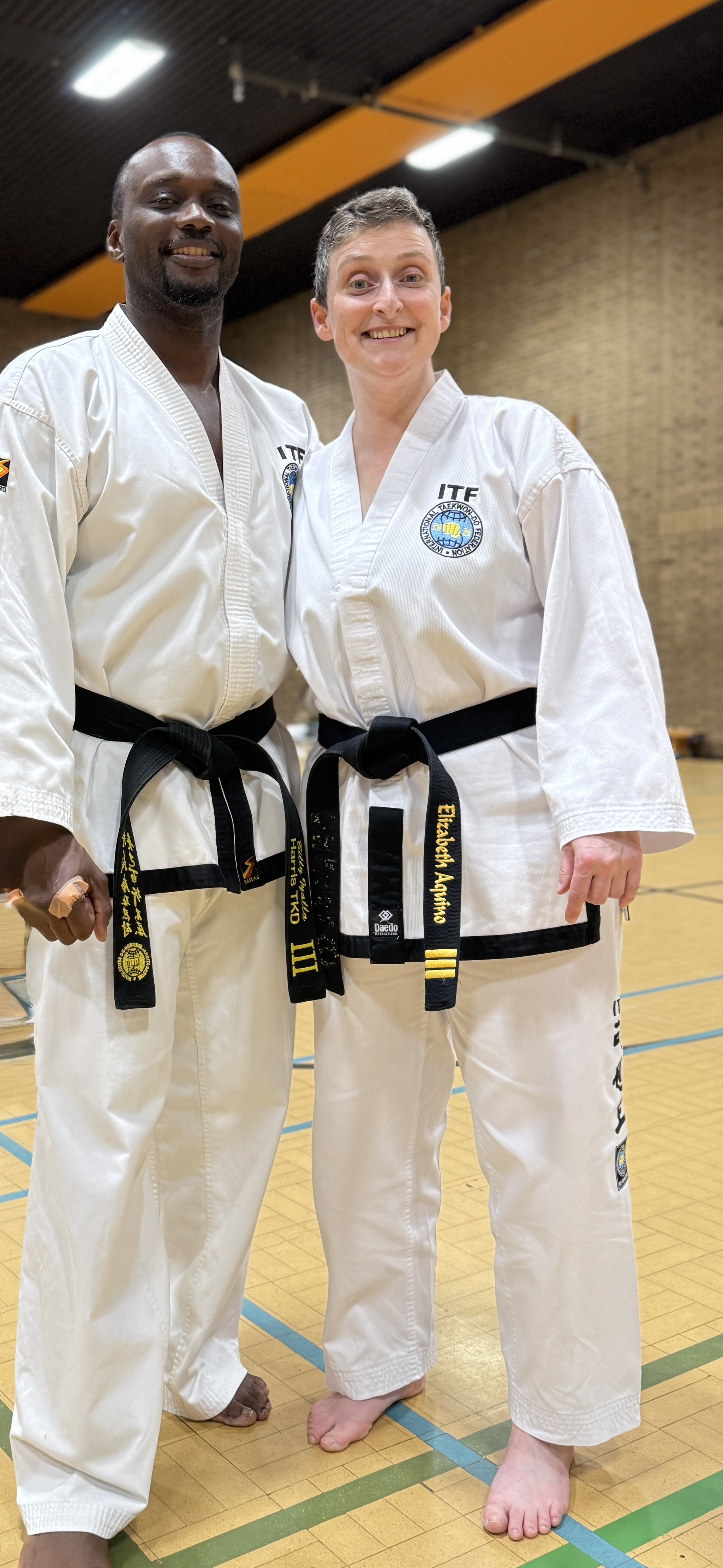 Eddie and Billie after their IV dan taekwon-do grading. Smiling to camera in dobok